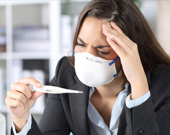 Photo of business woman holding a thermometre and wearing a mask